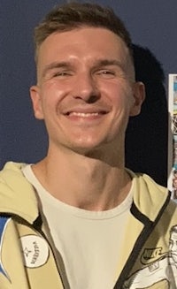 a young man smiling in front of a wall